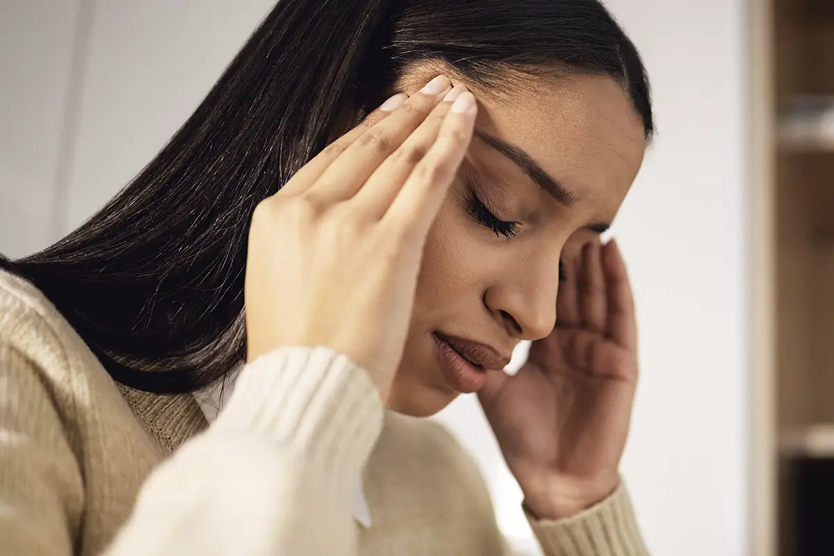 Woman experiencing dizziness and vertigo, holding her head in discomfort, emphasizing the impact of balance issues.