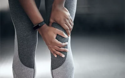 Person in athletic wear holding knee in pain, illustrating common knee issues related to physical therapy and rehabilitation.